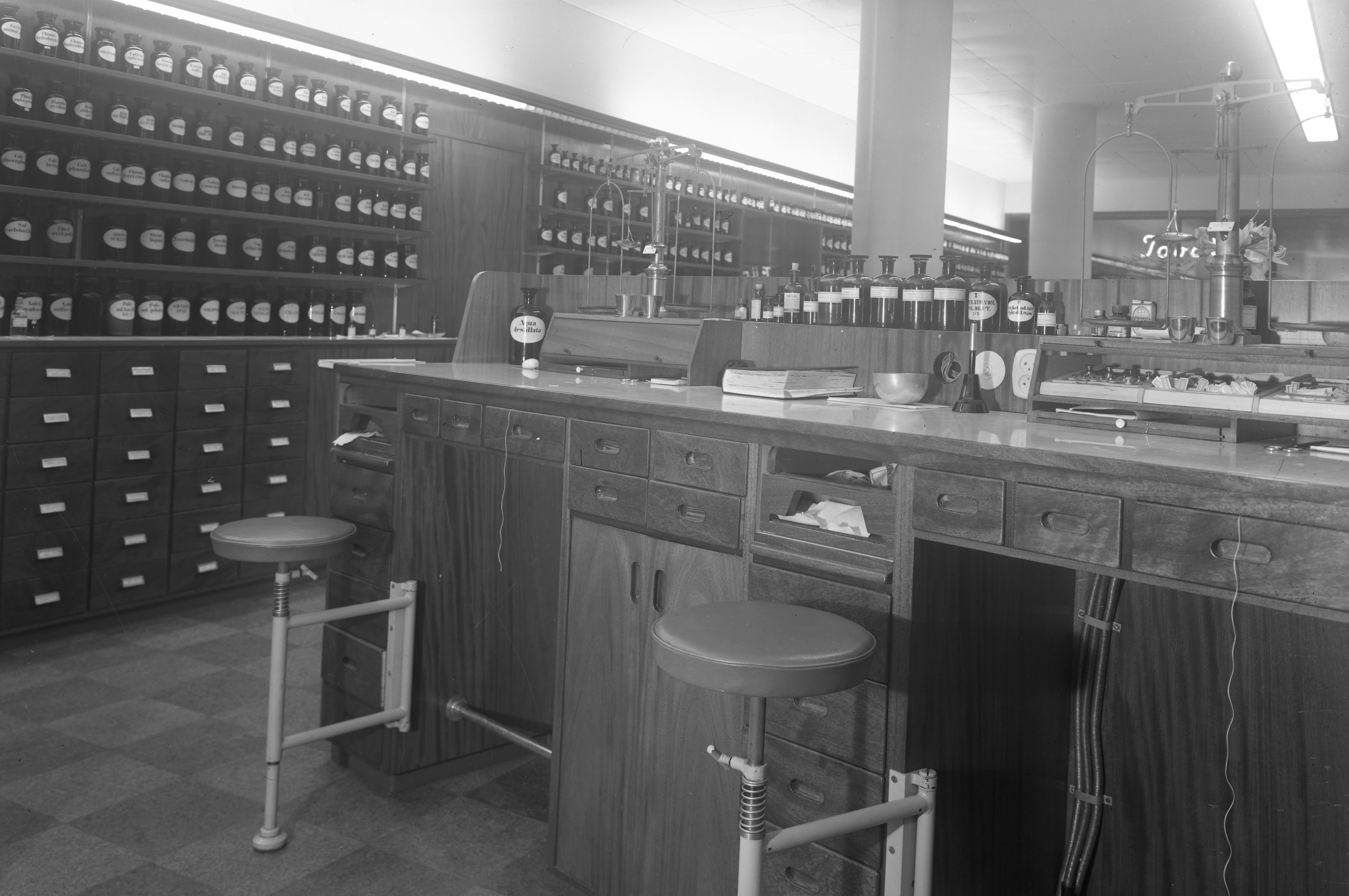 Apoteksdisk med många flaskor i bakgrunden, 1950-tal.